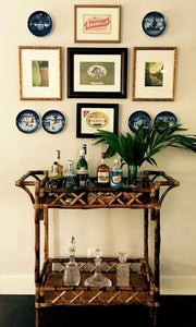 Kenian beverage stand and serving table against wall with framed art work above